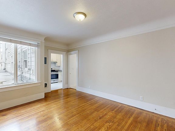 Sunlit room with a large window and wood-like flooring
