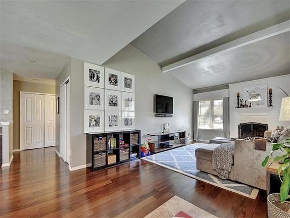 The vaulted and beamed living room features a cozy fireplace.