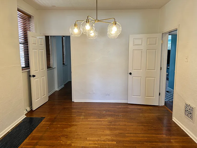 Dining room looking towards rear back of unit. Bedroom door on the left, and main hall with bathroom and kitchen to the right.