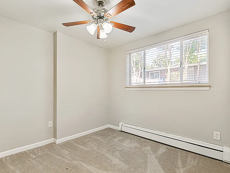 Bright and inviting room with fresh carpets, a ceiling fan, and a large window offering scenic views and ample natural light.