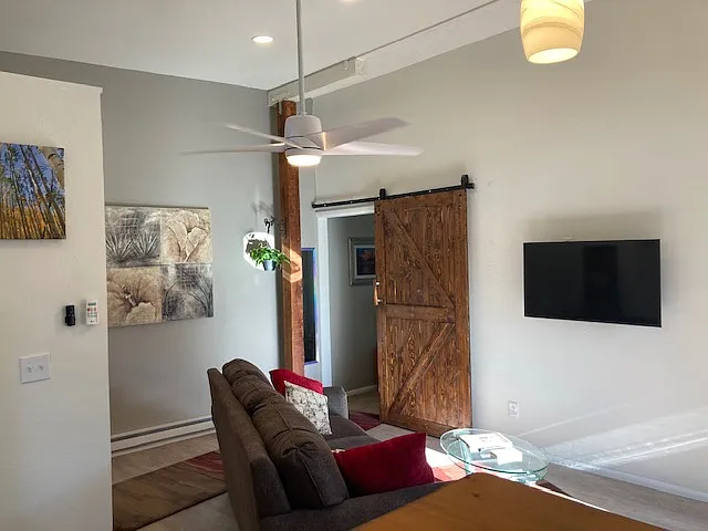 Living room with high ceiling. The barn door leads to bedroom