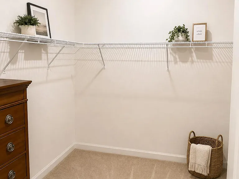 Walk-in closet with wraparound wire shelving and ample floor space for hanging clothes, shoes, and storage bins.