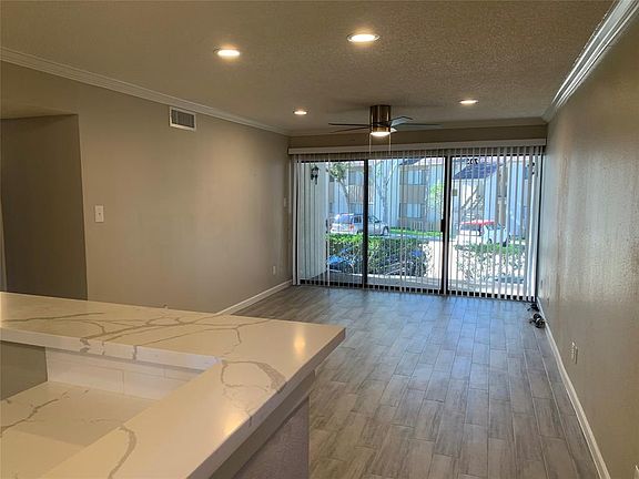 From the entry you see the open living room with wood look tile flooring, crown molding and new fan.
