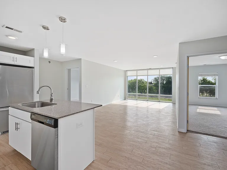 Bright and airy open-plan apartment featuring a modern kitchen with stainless steel appliances, spacious living area, and floor-to-ceiling windows offering scenic views. Bright and airy open-plan apartment featuring a modern kitchen with stainless steel a