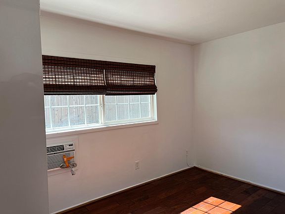 bedroom with double panel window, air conditioner and hardwood floor