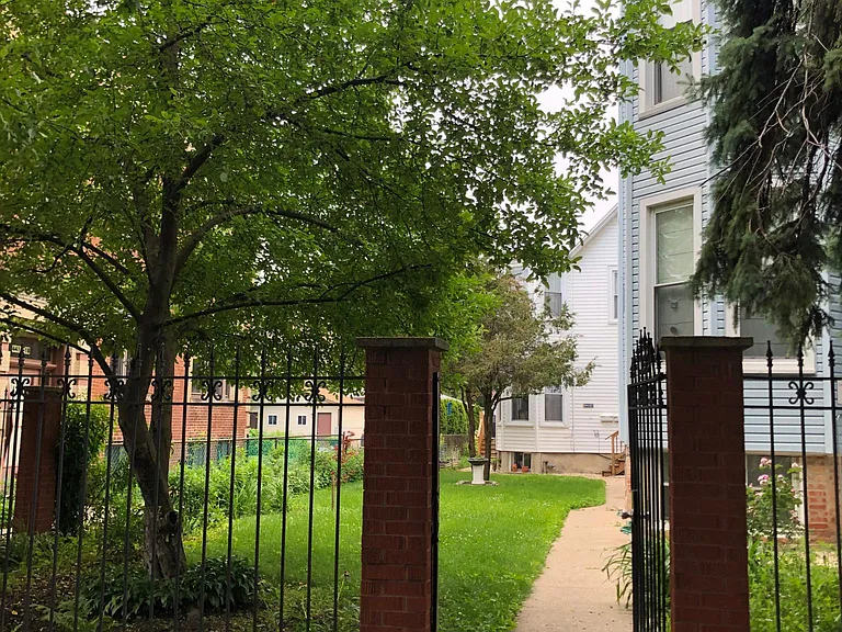 The unit is in the white coach house, behind the blue house.