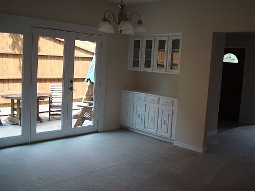 Dining room with french doors to landscaped patio with furniture. There is built-in china cabinets. 
