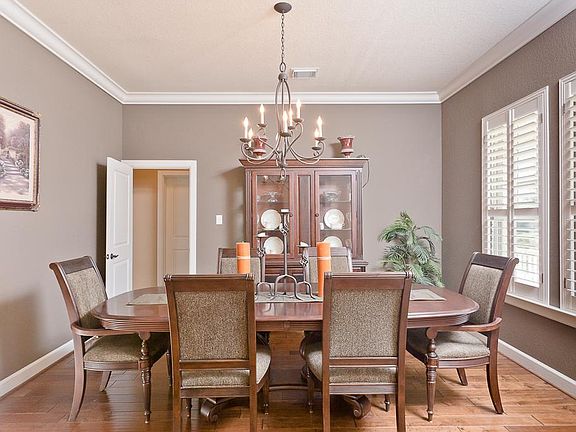 Large dining room with wood floors, crown molding, plantation shutters and decorator paint is easily accessible from kitchen.