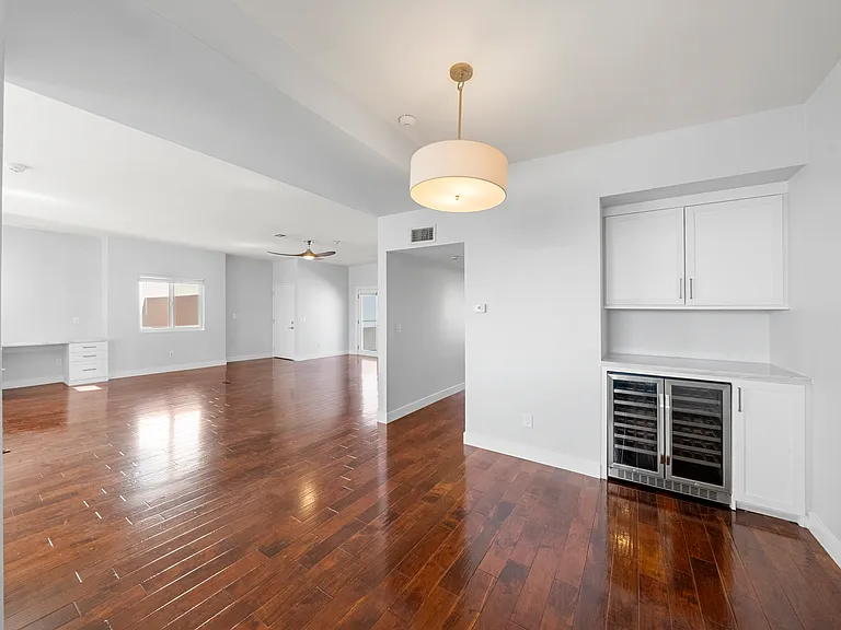 Dining area with wine fridge off the kitchen open to living room. Hallway leading to bathroom and upstairs guest bedroom