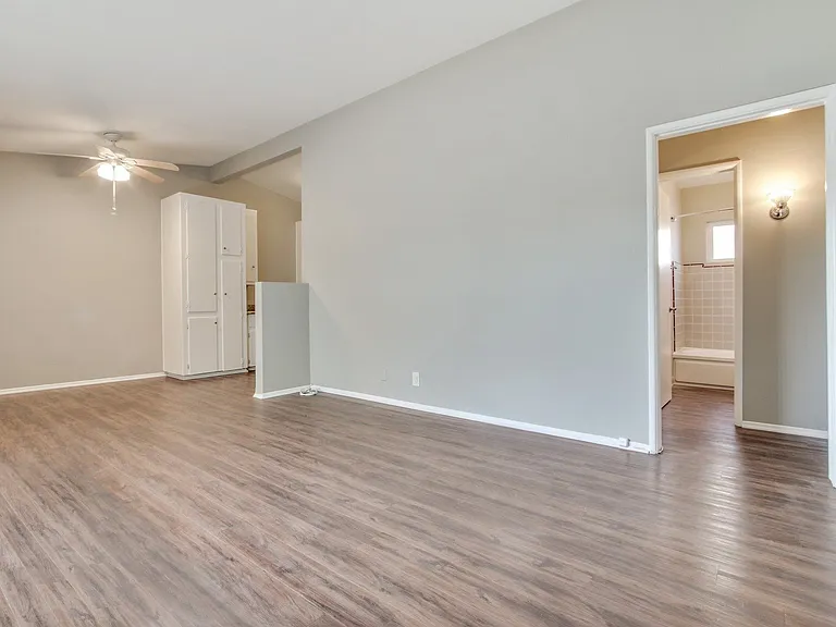 Living room wood-style floors throughout the unit, dining area with ceiling fan on the left