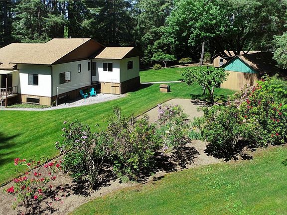 View from the southeast corner of the property; looking at the home on your left and the large garage on the right. Driveway terminates at the garages.