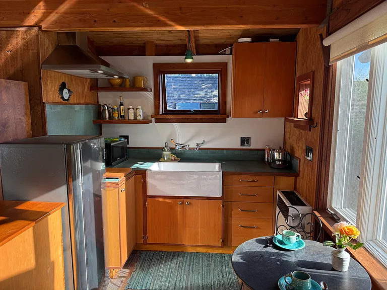 Kitchen with fridge, 2 induction burners, hood, farm sink, storage under cabinets and natural light from operable windows