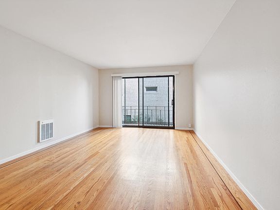 Sunlit room with a large window and wood-like flooring