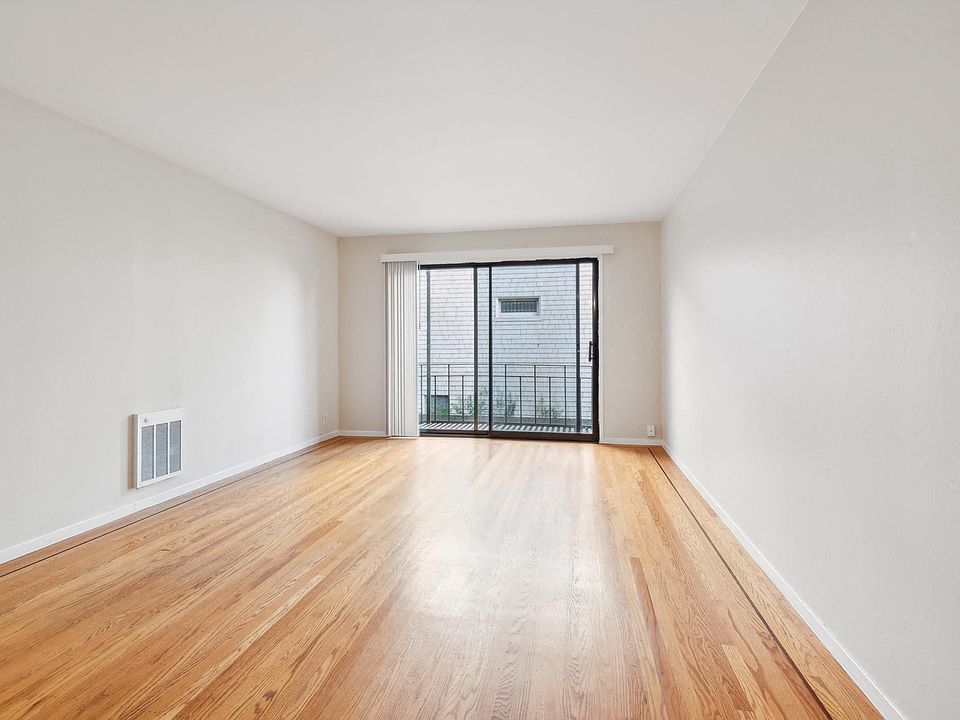 Sunlit room with a large window and wood-like flooring
