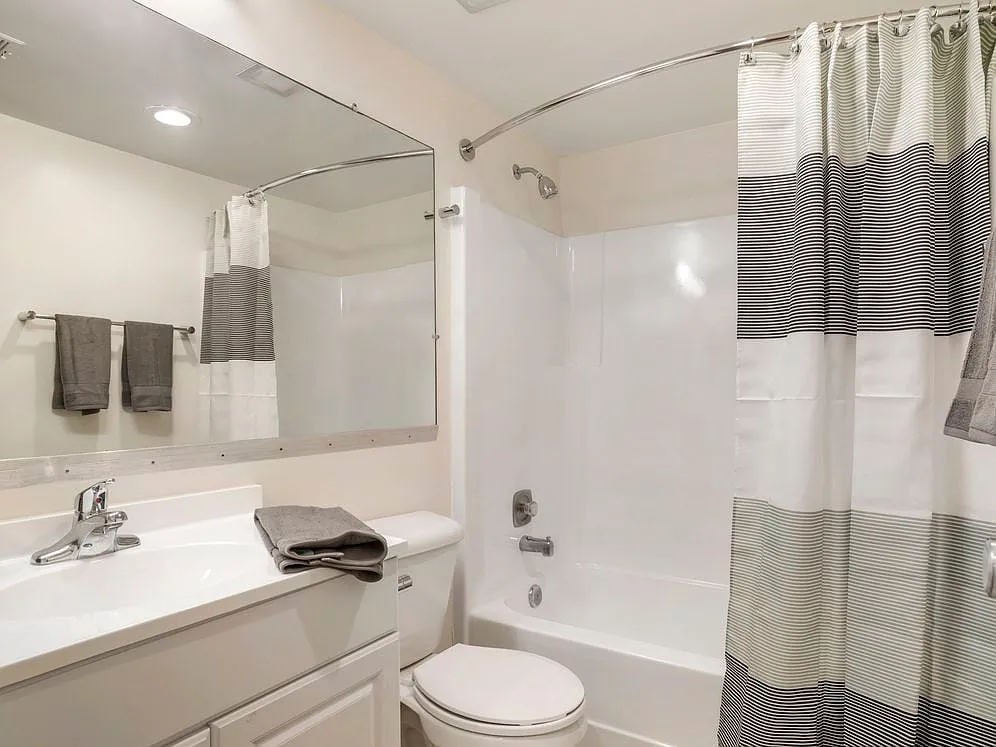 Renovated Package II bath featuring white cabinetry and countertops - eaves Tysons Corner