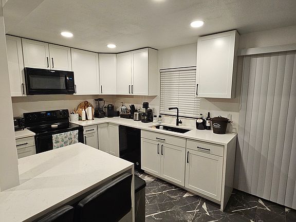 The kitchen features built-in Whirlpool appliances, including a refrigerator, dishwasher, stove, microwave, and garbage disposal. A deep farm-style sink adds both function and charm to the space.