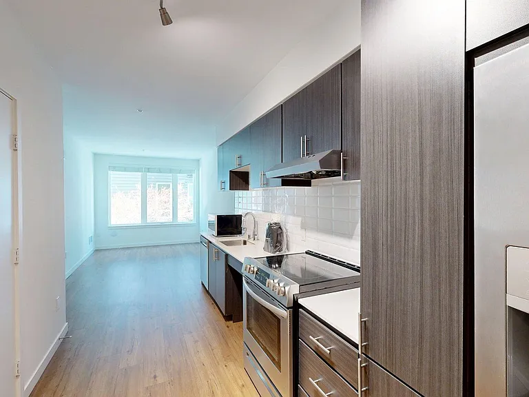 Apartment Kitchen with Stainless Steel Appliances, Dining and Living Room with Wood-Style Flooring.