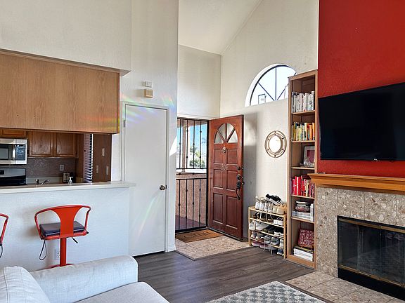 View from slider of the front door, fireplace, mantel, coat closet, built-in book shelves