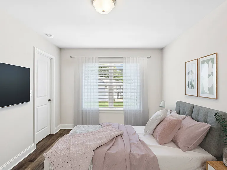 Secondary bedroom with queen bed, large sunlit window.