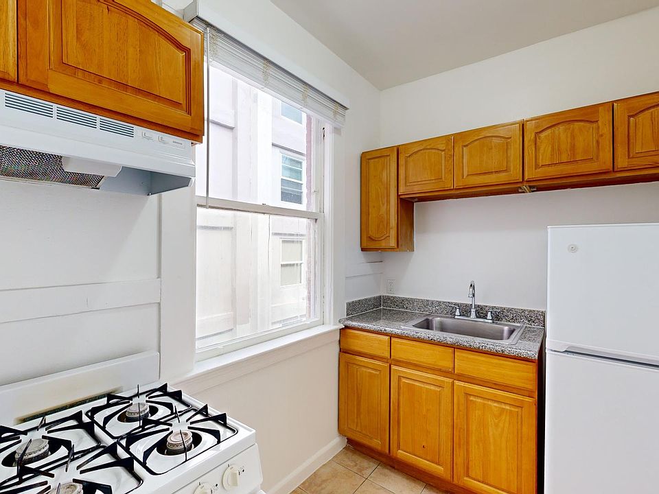 Compact kitchen with wooden cabinets, countertops, and a gas stove. A large window provides natural light, creating a bright and welcoming atmosphere.