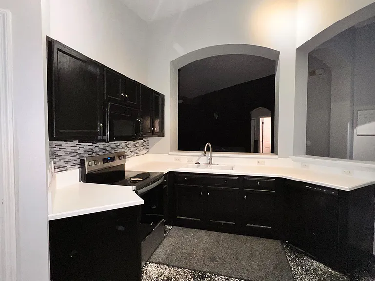 U-shaped kitchen with ample counter space, mosaic tile backsplash, and breakfast bar opening to the main living area.
