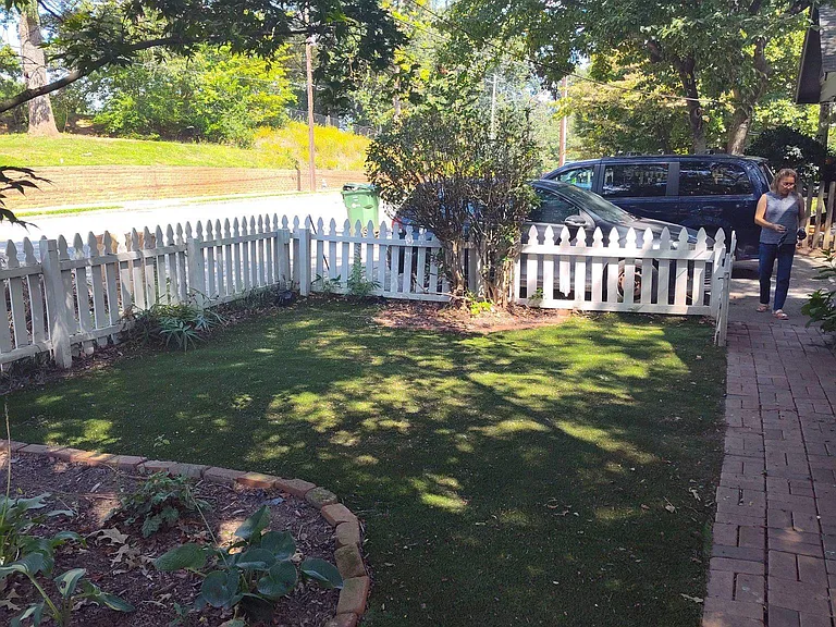 Charming front yard with white picket fence and bricked pathway