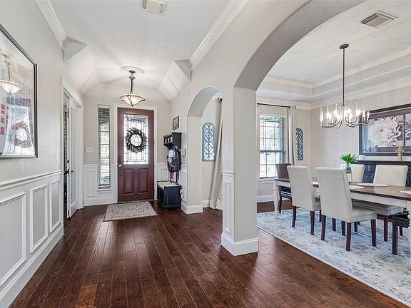 Many lovely architectural details of the home are shown from the entry- arched doors, crown molding, paneled walls, wood floors, and high ceilings!