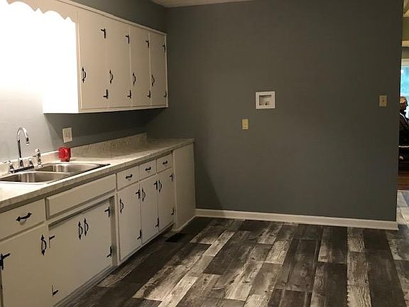Kitchen with lots of cabinets. 
Ice maker for refrigerator seen on wall.