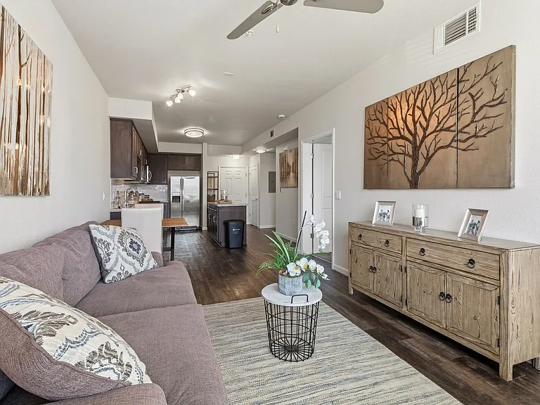 Aspire Apartments Tracy CA A living room with a blue chair and a painting of a tree on the wall.