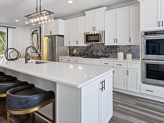Island kitchen with white stone counters in a DRB Homes Harlow Plan at WestRidge at Westphalia