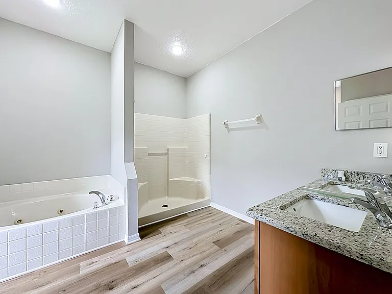 Spacious full bath with double-sink vanity, granite countertop, soaking tub, and separate shower stall.