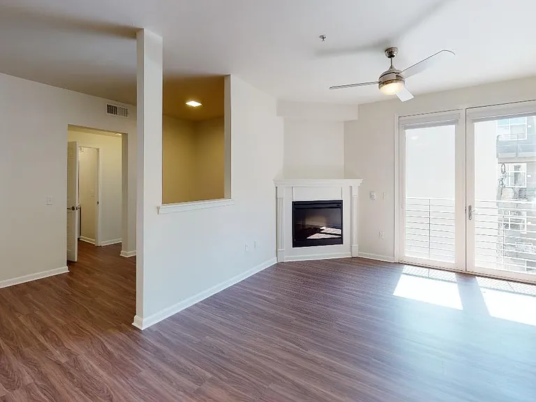 Apartment living room with wood-style flooring, fireplace and patio or balcony in select homes.