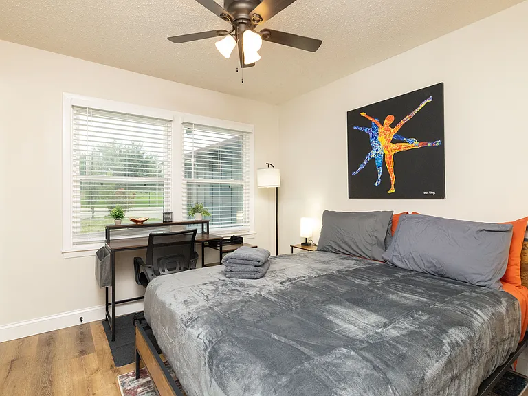 Bright bedroom with a comfy queen bed, dedicated workspace, large windows, and modern decor. Peaceful, stylish, and perfect for working or unwinding.