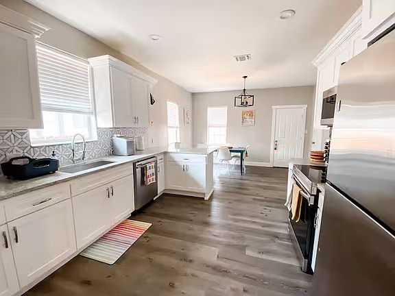 The bright, modern kitchen features abundant cabinet storage, generous counter space, updated appliances, a walk-in pantry, and clean white finishes throughout.