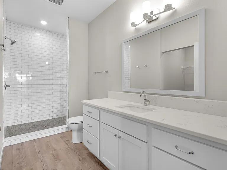 Elegant bathroom with a modern white vanity and spacious walk-in shower, featuring subway tile and sleek fixtures. Elegant bathroom with a modern white vanity and spacious walk-in shower, featuring subway tile and sleek fixtures.
