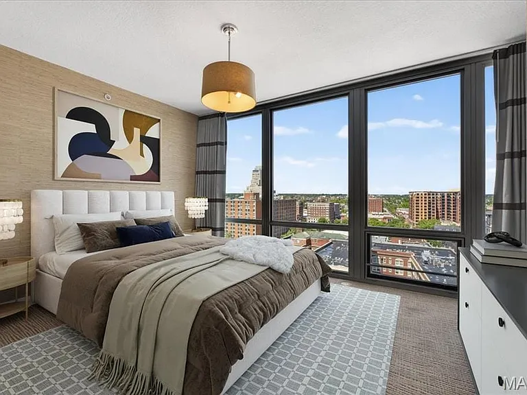 Spacious bedroom with full-height windows offering expansive urban scenery