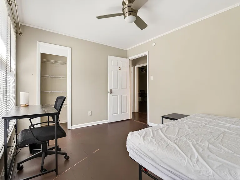 Bedroom with a ceiling fan, large window with blinds, open closet shelving, and a dedicated desk/workspace area.