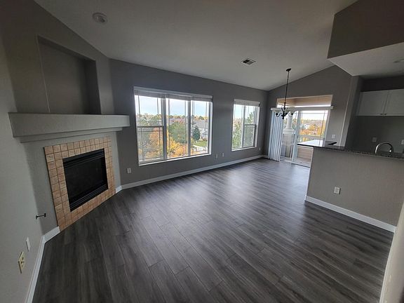 View of gas fireplace in the living room, large windows and balcony access from the dining area.