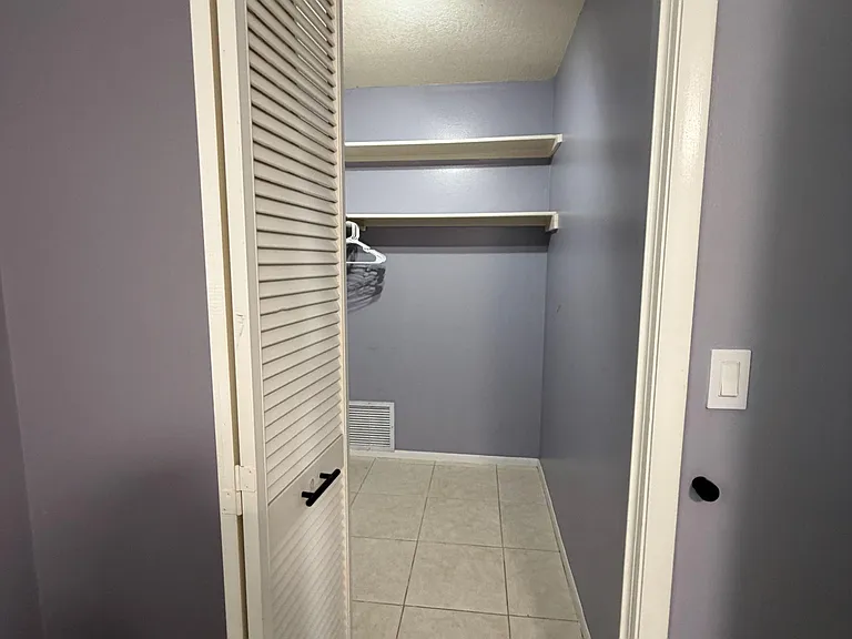 Spacious walk-in closet with built-in shelving and hanging space, plus tile flooring for easy upkeep.