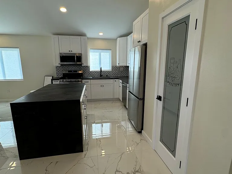 Kitchen with new SS appliances, quartz countertops, white shaker cabinets, workstation sink, island and under cabinet lighting.