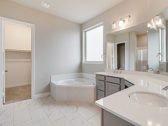 The primary bathroom has a walk-in shower with tile surround with a separate soaking tub and leads y
