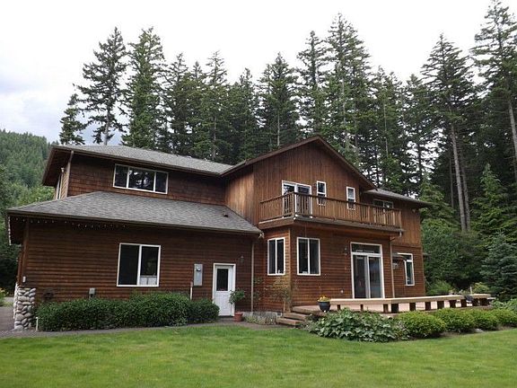 Back of home with huge entertainment sized deck overlooking beautiful level back yard and pristine r