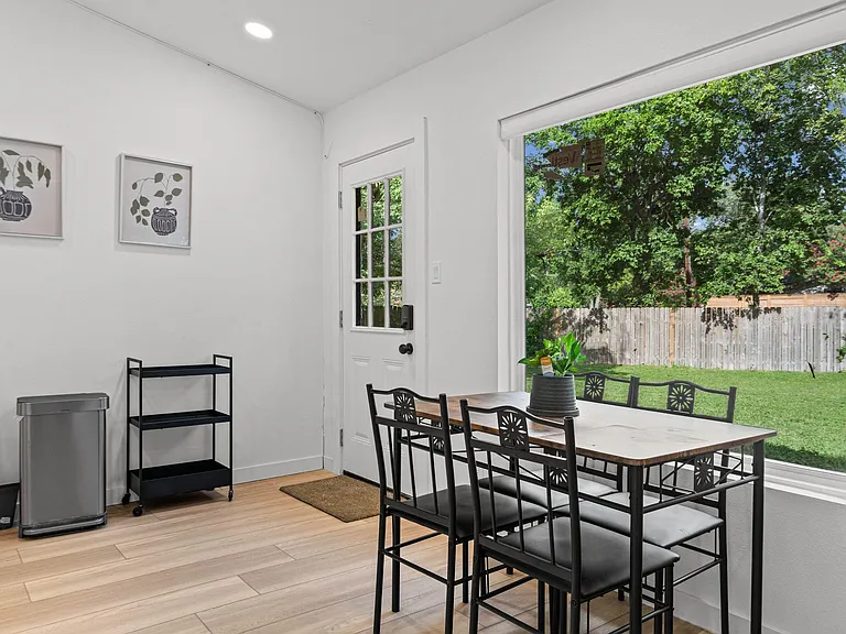 Dedicated dining area with a table for four, large picture window, and easy access to the backyard through a side door.