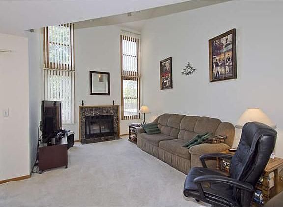 Living room with grand fireplace and large windows that let in plenty of natural light.