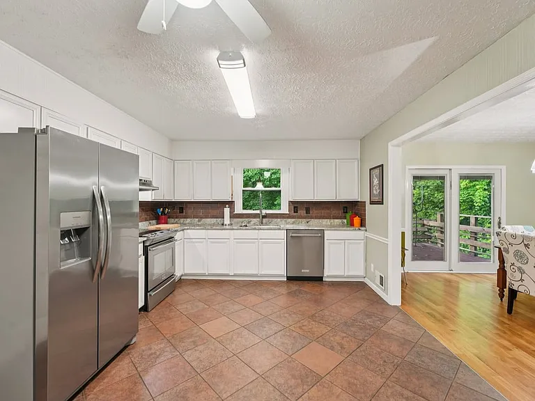 A bright and spacious kitchen where crisp white cabinetry, stainless steel appliances, and warm tile floors create a cheerful setting for everyday meals and enchanted gatherings.