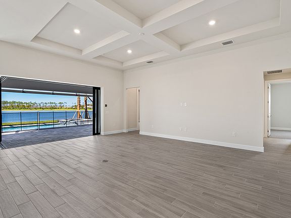 Gathering room with a decorative coffered ceiling a zero-corner slider leading to the pool