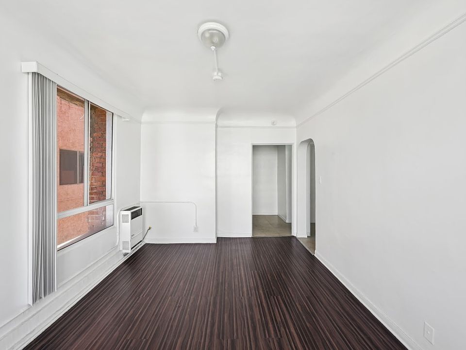 Union a bedroom with a large window and hardwood floors