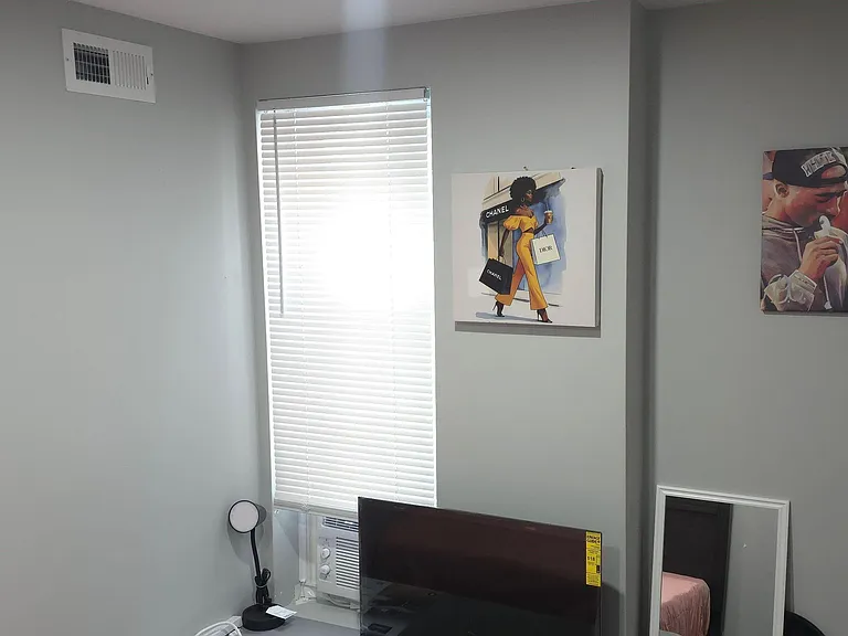 Private bedroom area with a window and blinds, plus in-room A/C for comfort and space for a TV or work setup.