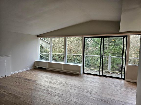 Living room with vaulted ceilings, wall of windows that looks out on to Ravenna Park, brand new engineered hardwood floors! Sliding doors open to deck!