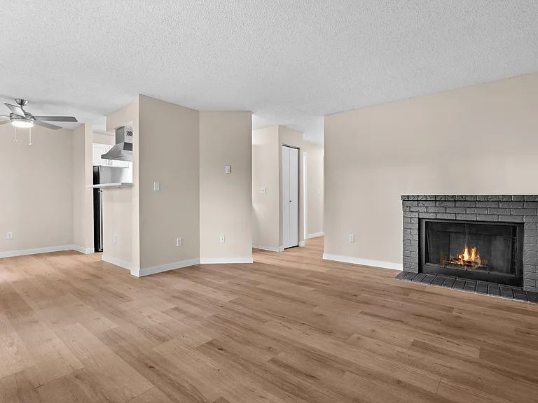A spacious apartment living room with warm wood-style flooring, an inviting brick fireplace, and an open layout ready to make your own. A spacious apartment living room with warm wood-style flooring, an inviting brick fireplace, and an open layout ready t